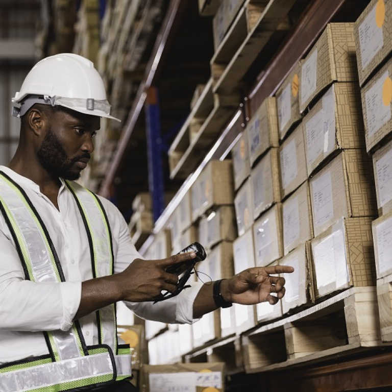 Black male staff using digital barcode scanner working checking stock in logistic warehouse