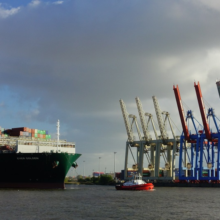 big containership let by a tug boat in hamburg harbor